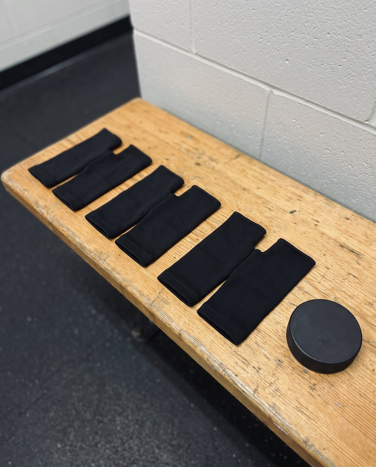 Six Olyra Blister Sleeves, three pairs, laid out on a dressing room bench next to a puck