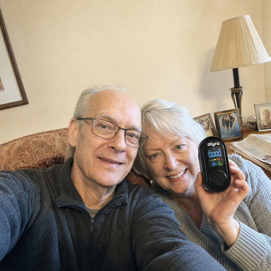 An older couple holding the TrueDetect detector in their living room.